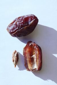 Close-up flat lay of whole and half dates with seed on a white background.