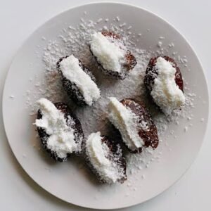 Delicious vegan coconut-stuffed dates on a white plate, perfect for healthy indulgence.